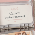 Femme écrivant dans un carnet de budget coloré pour organiser ses finances, avec des fournitures de bureau à proximité.